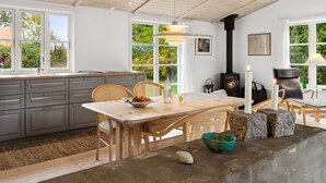 Una cocina moderna con una isla grande, techo de madera y chimenea de piedra.