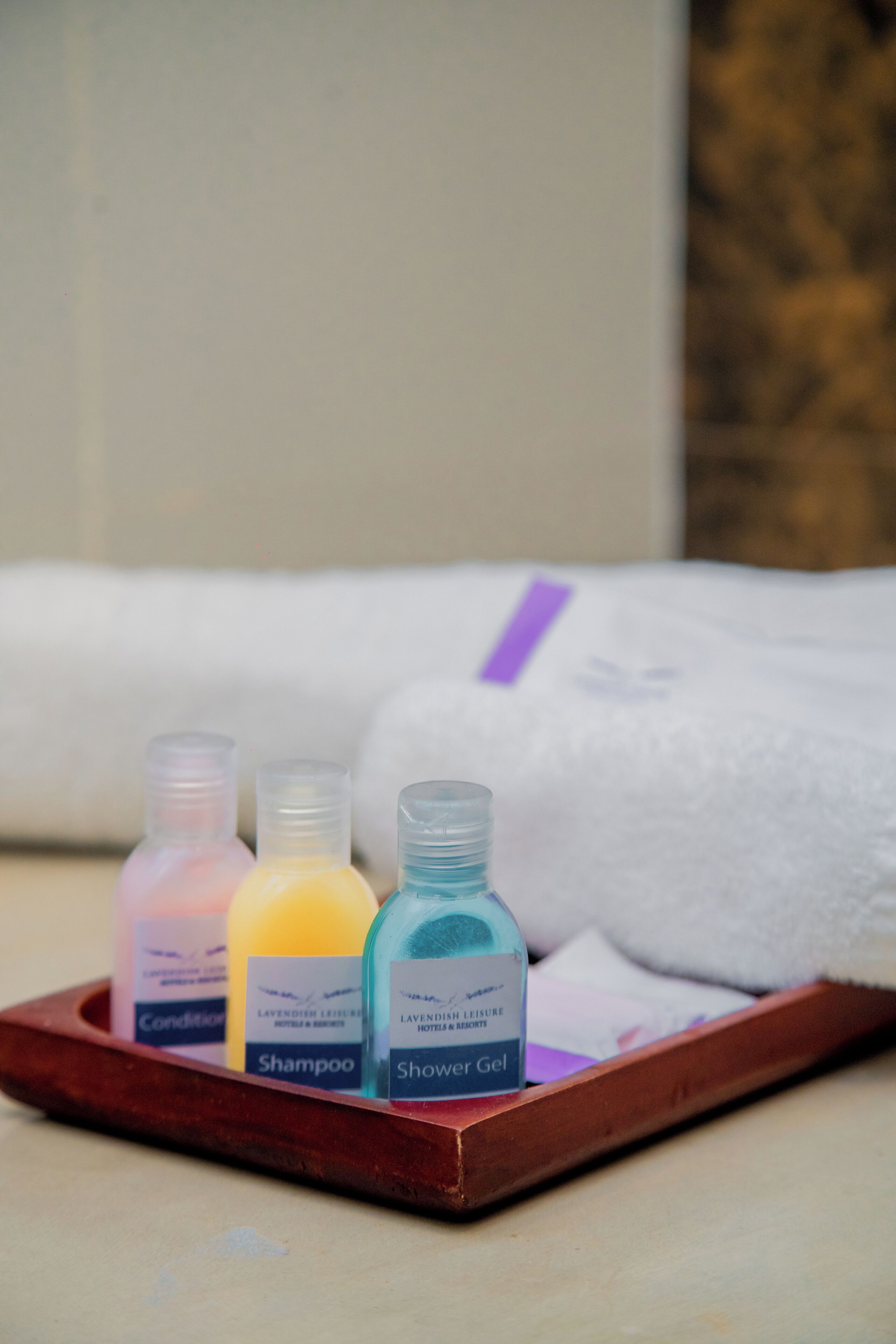 A tray with three bottles of toiletries: conditioner, shampoo, and shower gel.