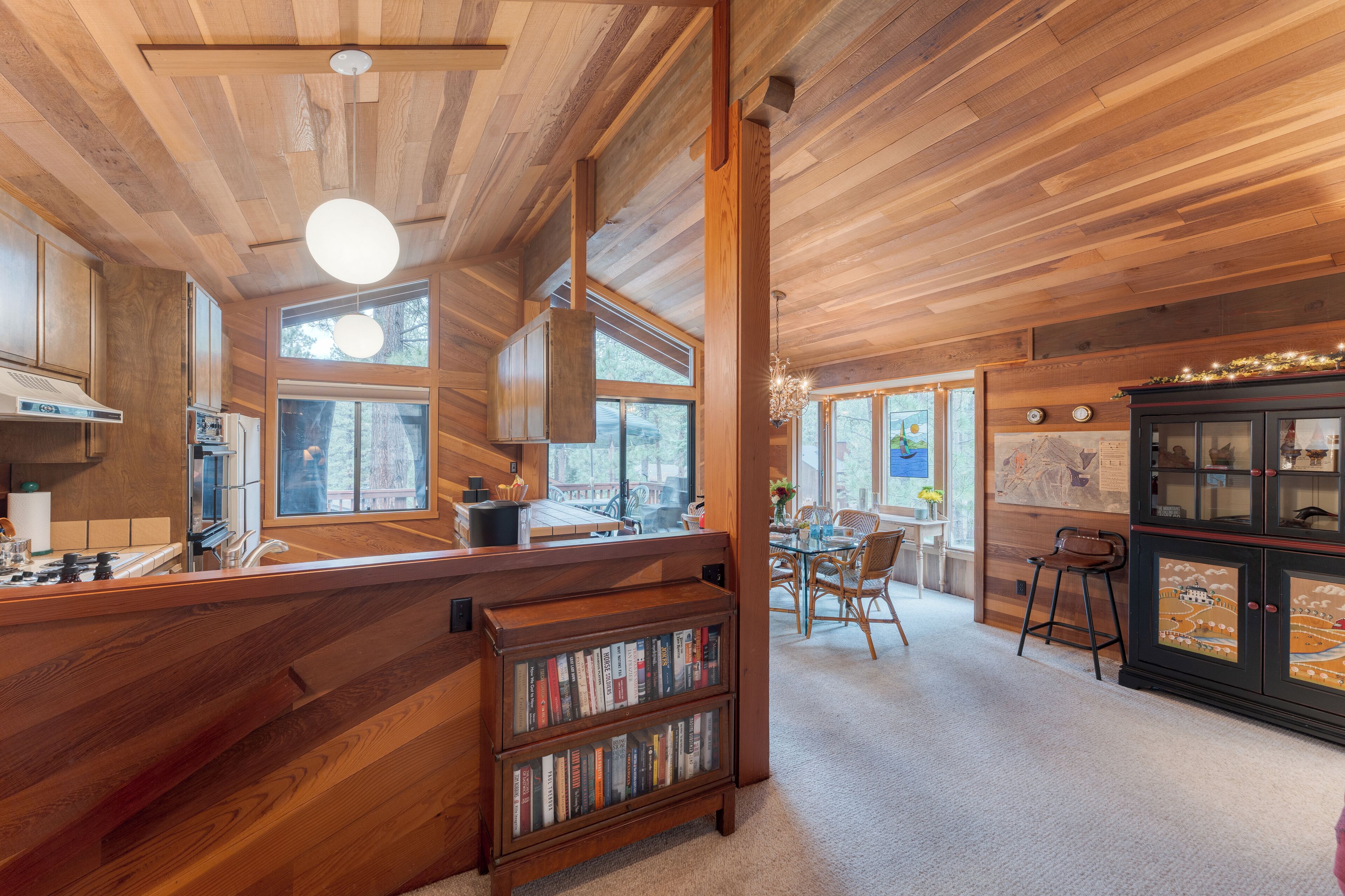 A wooden interior with a kitchen, dining area, and a bookshelf.