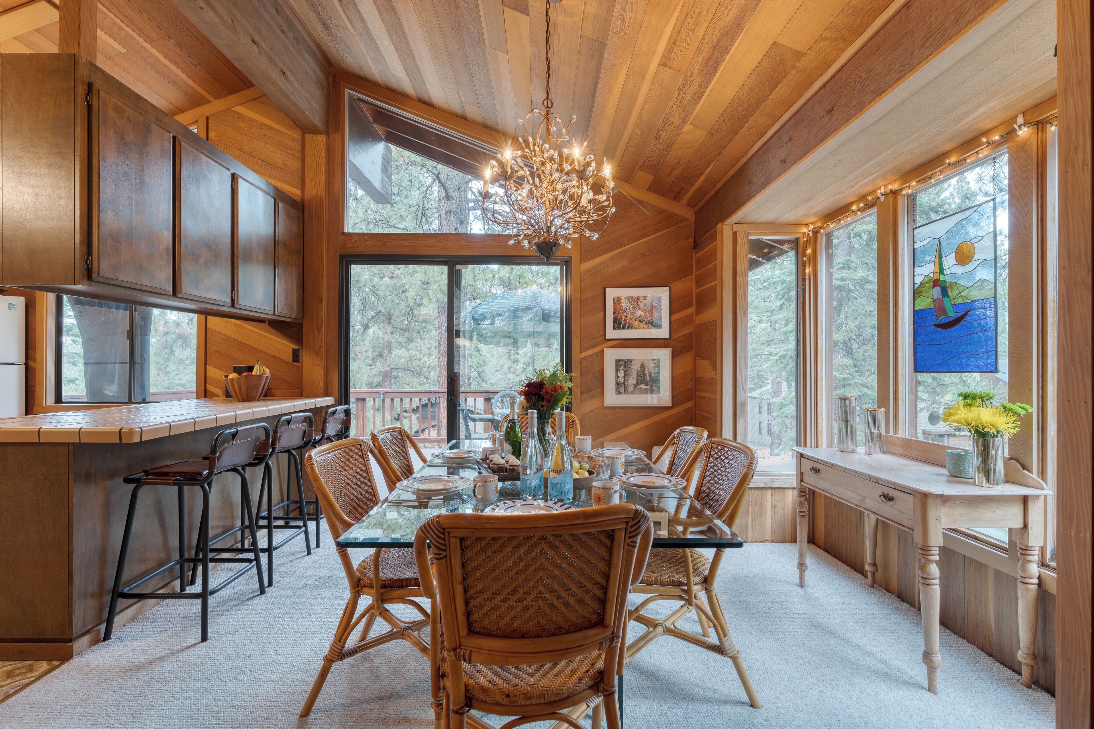 Un interior de madera con comedor, ventanas amplias y una araña.