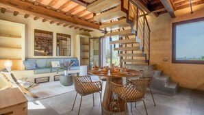 A modern interior with a spiral staircase, a round dining table, wicker chairs, and a sofa with cushions. - Lovely apartment with pool, A/C, WIFI, TV, veranda and panoramic view, close to San Gimignano (Montaione)