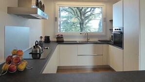 Una cocina moderna con un amplio ventanal, electrodomésticos integrados y techo de madera.