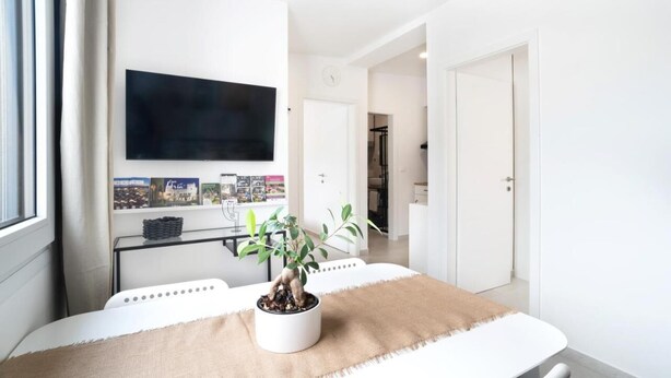 Una sala de estar moderna con una televisión de pantalla plana en la pared, una mesa de centro con una planta en maceta y un sofá.
