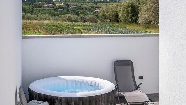 Μια εξωτερική μπανιέρα υδρομασάζ σε ένα μπαλκόνι με θέα σε ένα αγροτικό τοπίο.