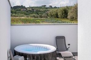 Een bubbelbad op een balkon met uitzicht over het landschap.