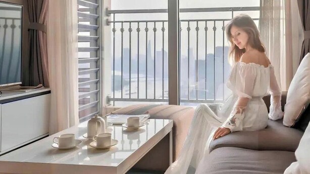 A room with a balcony, a bed, a TV, and a table with cups and saucers. - YoungC Apartment Landmark (Ho Chi Minh City)