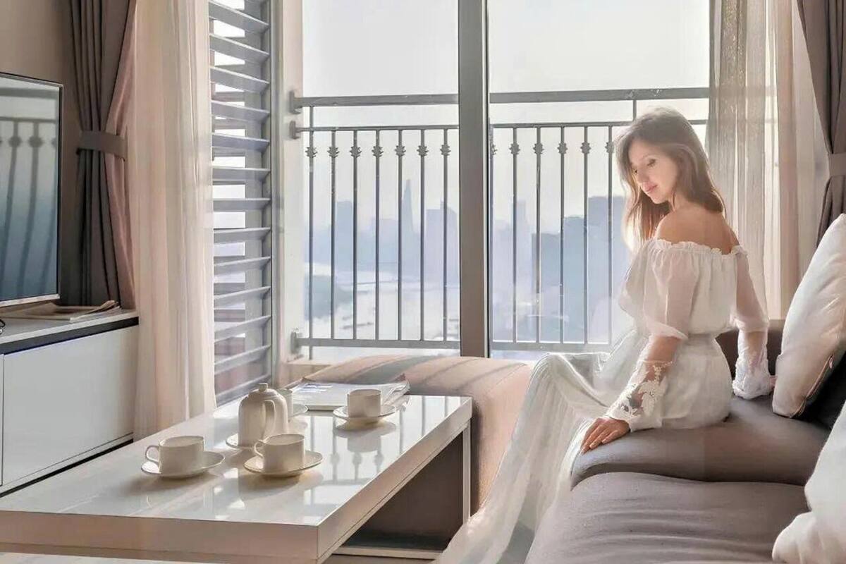 A room with a balcony, a bed, a TV, and a table with cups and saucers.