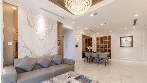 A modern living room with a marble wall, a grey sofa, a marble coffee table, and a chandelier. - YoungC Apartment Landmark (Ho Chi Minh City)