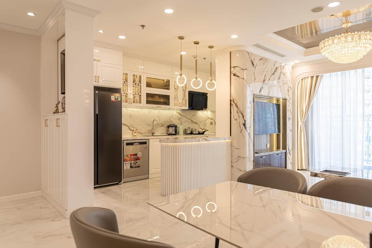 A modern kitchen with marble countertops, a central island, and pendant lighting.
