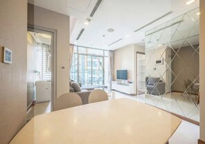 Une salle de réunion moderne dotée d’une grande table, de sièges confortables, d’un téléviseur et d’une cloison en verre.