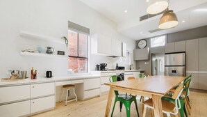 Una cucina moderna con mobili bianchi, un tavolo da pranzo in legno, sedie verdi e un'ampia finestra.