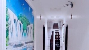 Un couloir orné d’une fresque représentant une cascade, avec des murs blancs et un sol carrelé.