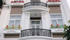 Un hôtel à plusieurs étages, doté d’une architecture classique, avec des balcons agrémentés de garde-corps décoratifs et de jardinières.