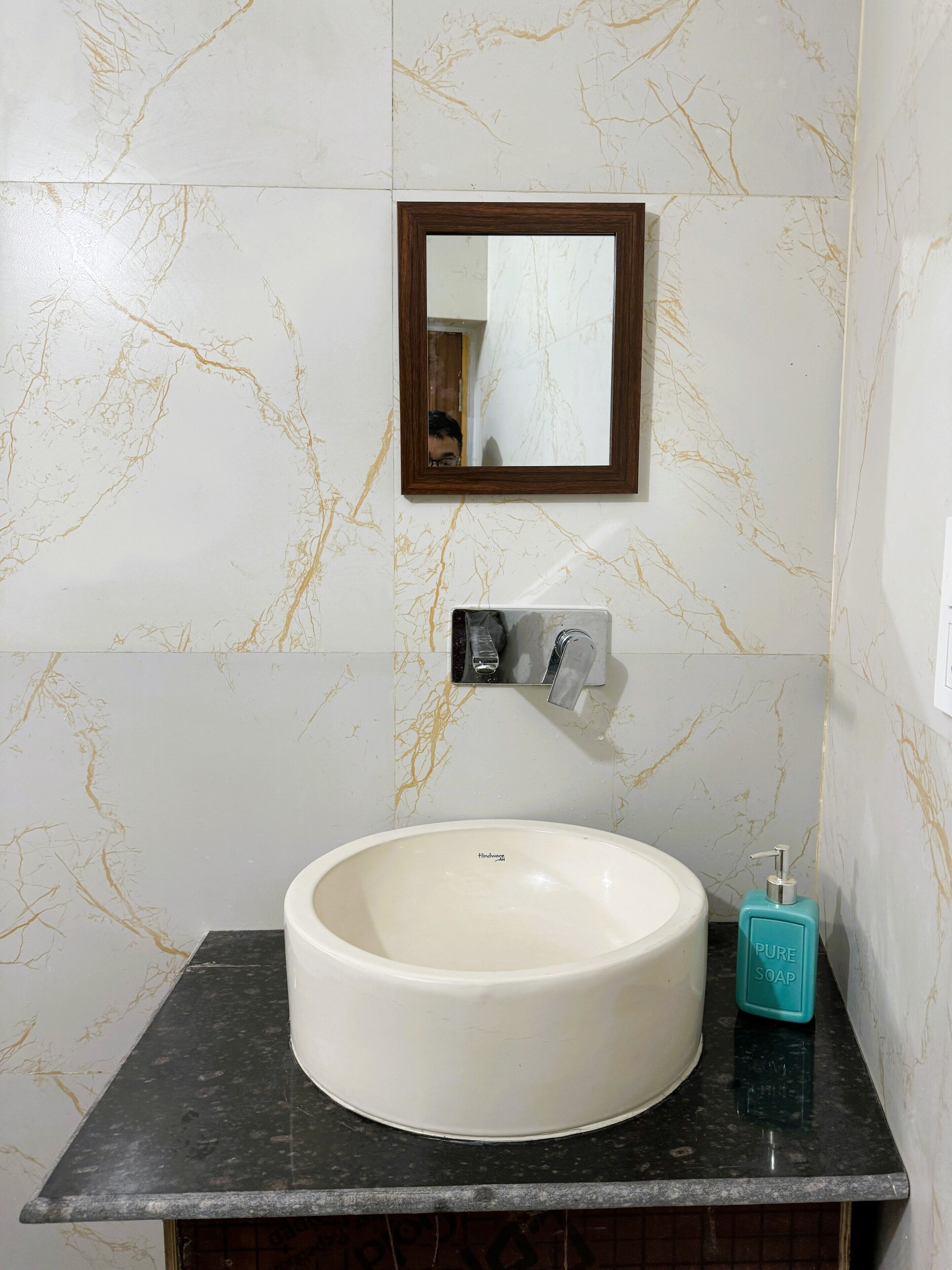 A bathroom with a white marble sink, a mirror, and a soap dispenser.