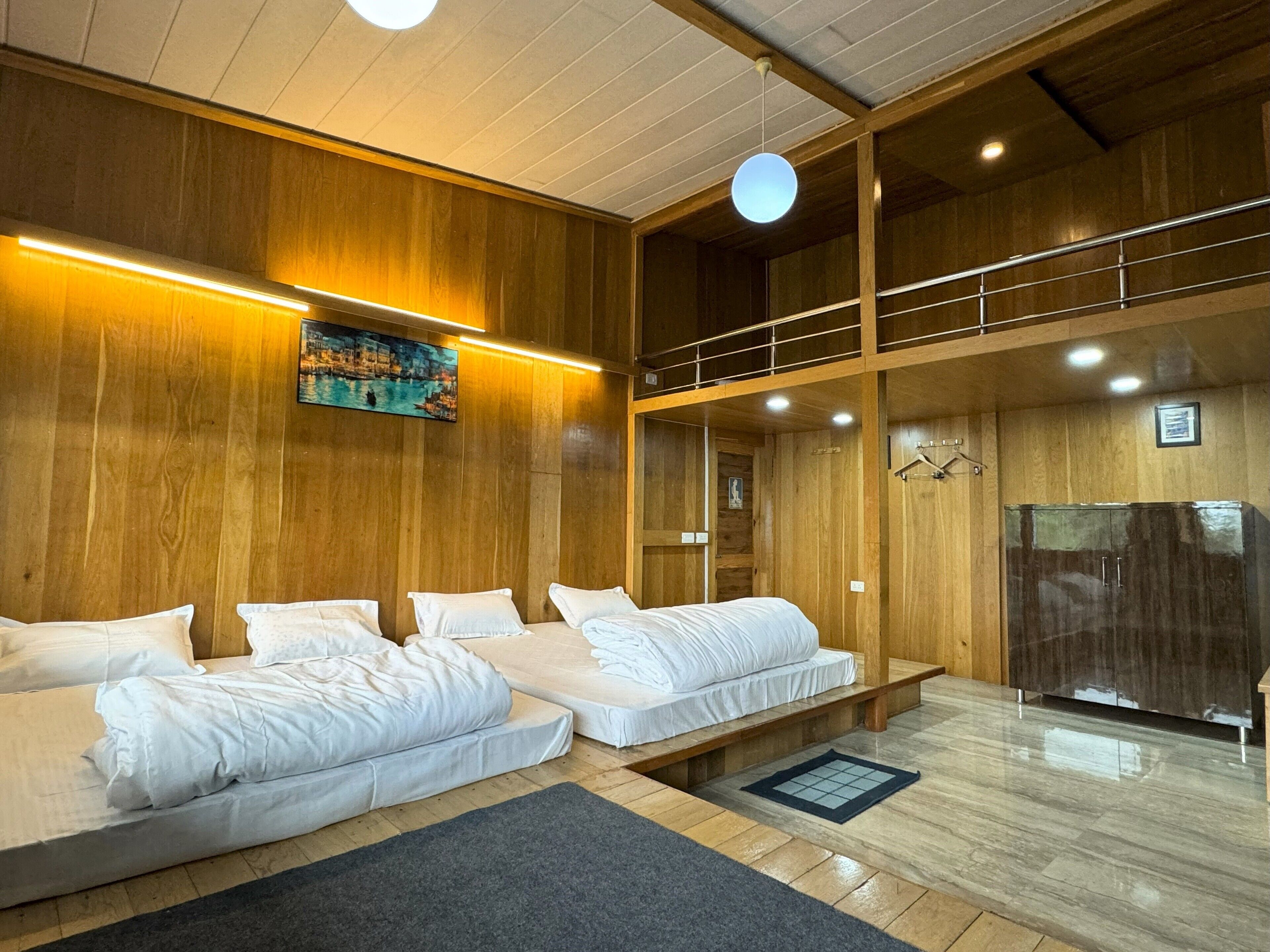 A hotel room with wooden paneling, a painting, a bed with white linens, a bench, a mirror, and a wardrobe.