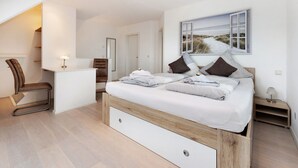 A bedroom with a bed, a desk, a chair, and a painting on the wall.