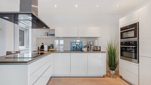 A modern kitchen with white cabinetry, a central island, and built-in ovens.