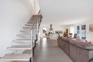 A modern interior with a staircase, a kitchen area, and a seating area with a sofa. - Apartment 'Palstek - Steinhude' with Lake View, Private Terrace and Wi-Fi (Wunstorf)