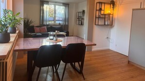 A dining area with a wooden table, two black chairs, a glass vase, and a candle on a placemat. - Apartment 'Ferienwohnung Liese' with Private Terrace, Private Garden and Wi-Fi (Detern)