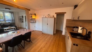 A modern kitchen with wooden cabinets, a dining area with a table and chairs, and a view of the outdoors through a window. - Apartment 'Ferienwohnung Liese' with Private Terrace, Private Garden and Wi-Fi (Detern)