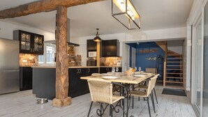 Eine moderne Küche mit dunklen Schränken, einem Holztisch und einer Pendelleuchte.