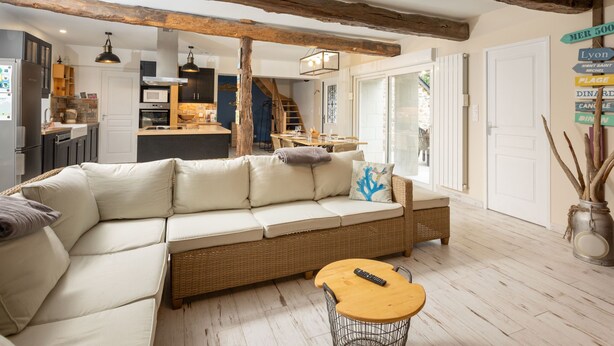Ein modernes Wohnzimmer mit einem großzügigen, L-förmigen Sofa, einem Holztisch und einem rustikalen Deckenbalken.