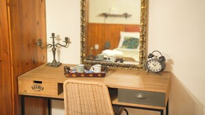 Un bureau en bois avec un miroir, un plateau contenant des tasses, un chandelier et une horloge.