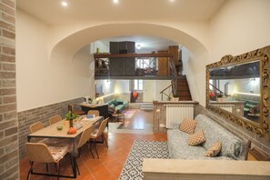 Un comedor amplio con techo alto, una escalera que sube a un nivel superior y un espejo grande en la pared.