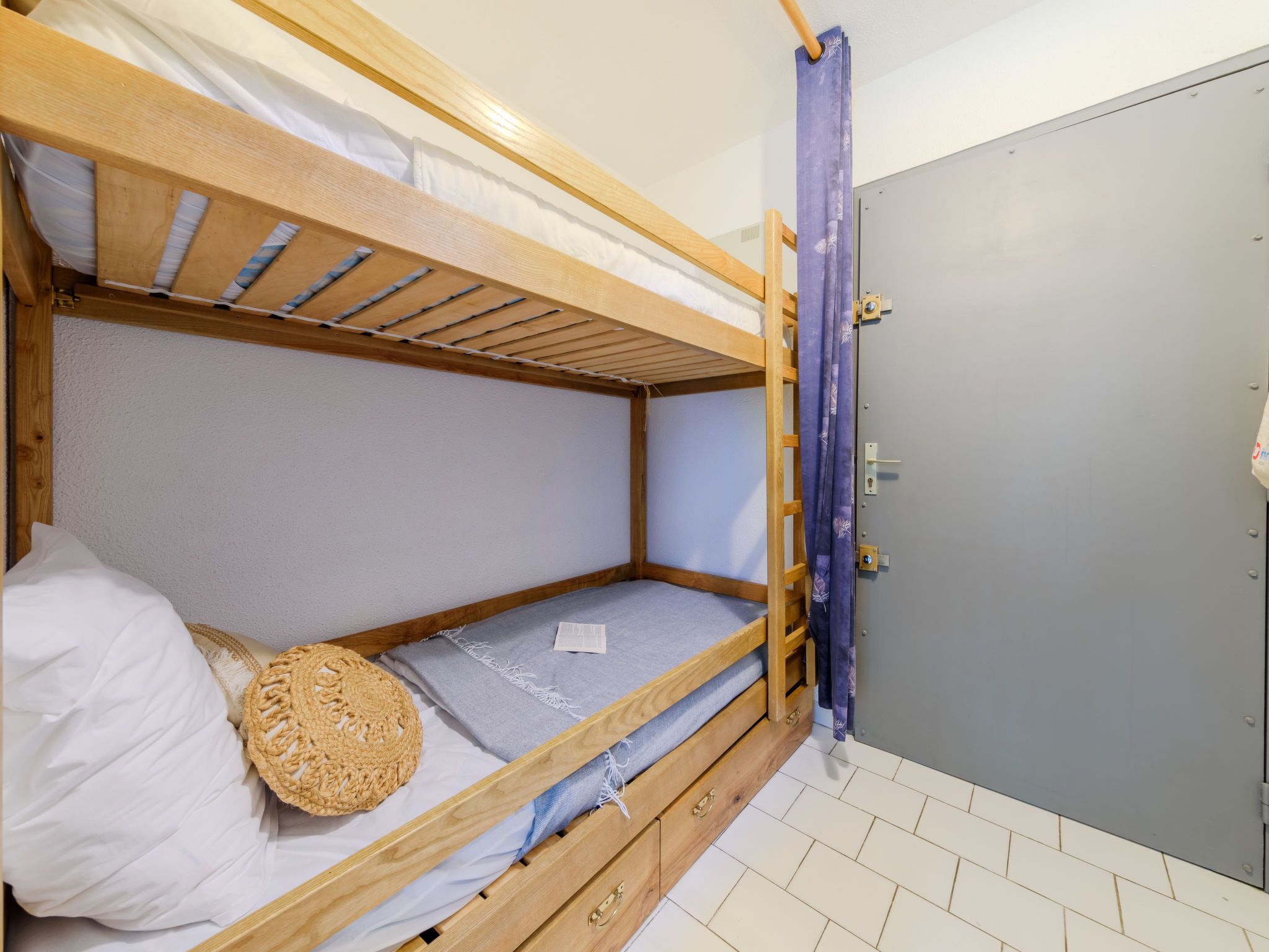 A bunk bed with a wooden frame, a single mattress, and a woven basket.
