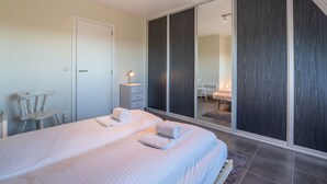 A modern bedroom with a large bed, a bedside table, a wardrobe, and a mirror. - Marebelle with seaview by Interhome (Bredene)
