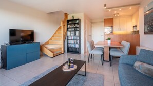 A modern living room with a TV, sofa, coffee table, and a staircase leading to a dining area. - Marebelle with seaview by Interhome (Bredene)