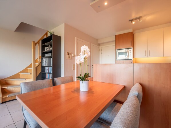 A modern kitchen with wooden cabinets, a built-in microwave, and a staircase leading to a lower level.