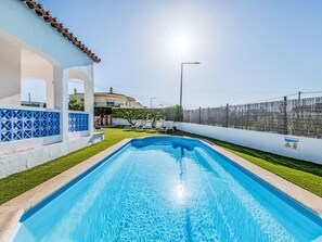 Une piscine à l’eau d’un bleu limpide, entourée d’un mur blanc orné de motifs bleus et d’une clôture.