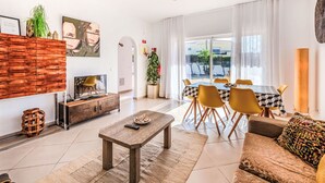 Una sala de estar moderna con sofá, mesa de centro, televisor y comedor con sillas y una mesa.