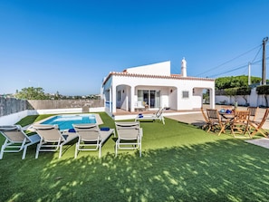 Une villa blanche avec une piscine, un espace salon extérieur et une vue sur la mer.