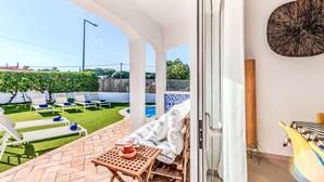 Un patio con piscina, sillas de descanso y una mesa con un libro y un sombrero.