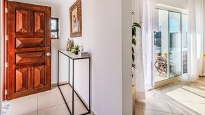 Un interior moderno con una puerta de madera, una consola y una puerta de cristal que da a un balcón.