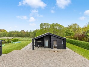 A modern, single-story building with a sloped roof, a covered outdoor area, and a well-maintained lawn.