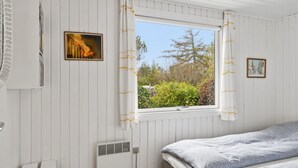 A bedroom with a bed, a window with curtains, a radiator, and a wall-mounted heater.