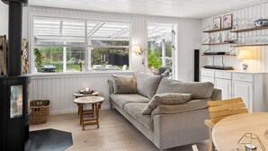 A cozy living room with a fireplace, a sofa, a small wooden table, and a dining area.