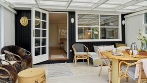 A cozy room with wicker furniture, a wooden table, and a large window.