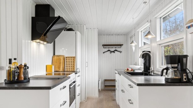 A modern kitchen with white cabinetry, a central island, and a coffee maker.