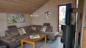 A cozy living room with a sectional sofa, a wooden coffee table, and a wood-burning stove. - exklusives skandinavisches Ferienhaus (Granzow)