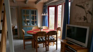 A dining area with a wooden table and chairs, a cabinet with glass doors, and a television on a wooden stand. - exklusives skandinavisches Ferienhaus (Granzow)