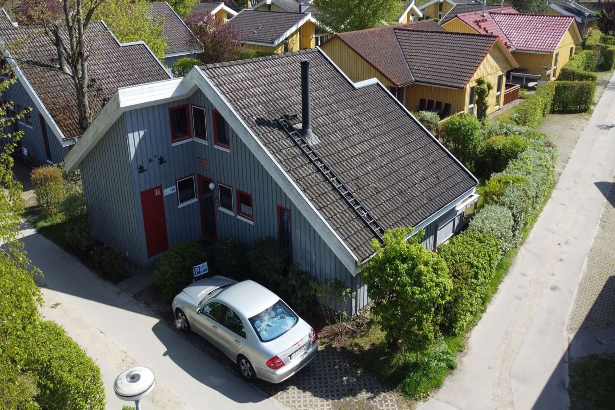 A residential building with a sloped roof, a car parked in front, and a visible chimney.
