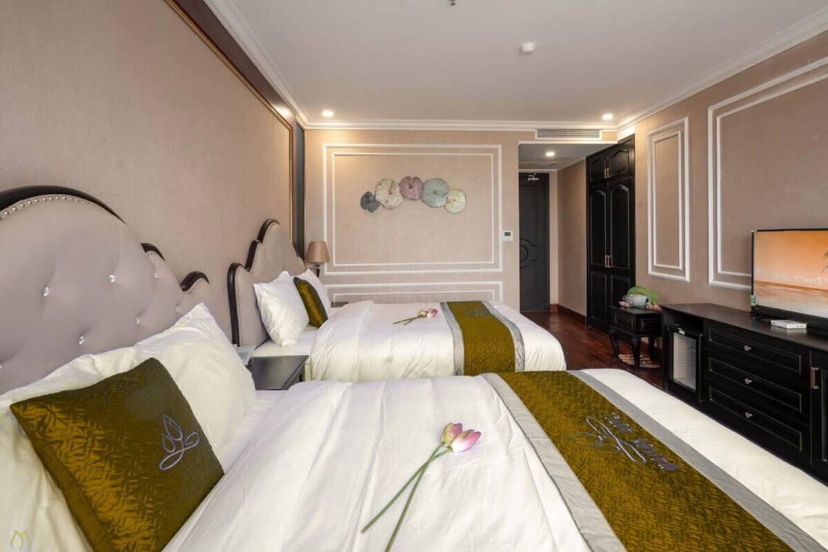 Habitación de hotel con dos camas, televisión y escritorio.