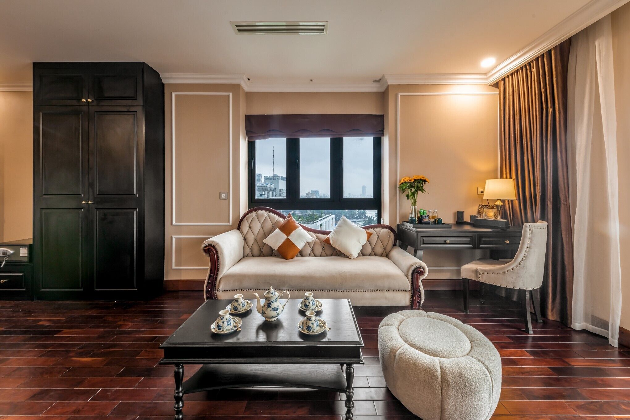 Amplia sala de estar con sofá, mesa de centro y un sillón. Se aprecia un ventanal con vistas a la ciudad.