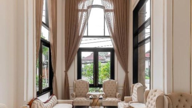 Un amplio salón con techo alto, ventanas grandes y una zona de estar con sofás y sillones.