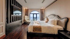 Un dormitorio con una cama grande, una silla, un televisor y vista al mar.