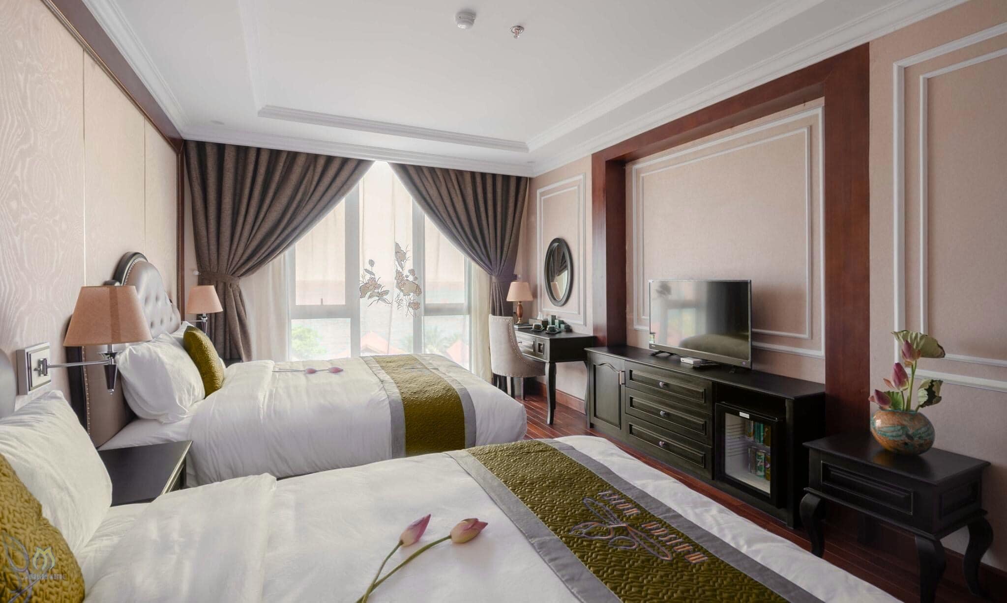 A hotel room with two beds, a television, a desk, and a dresser.